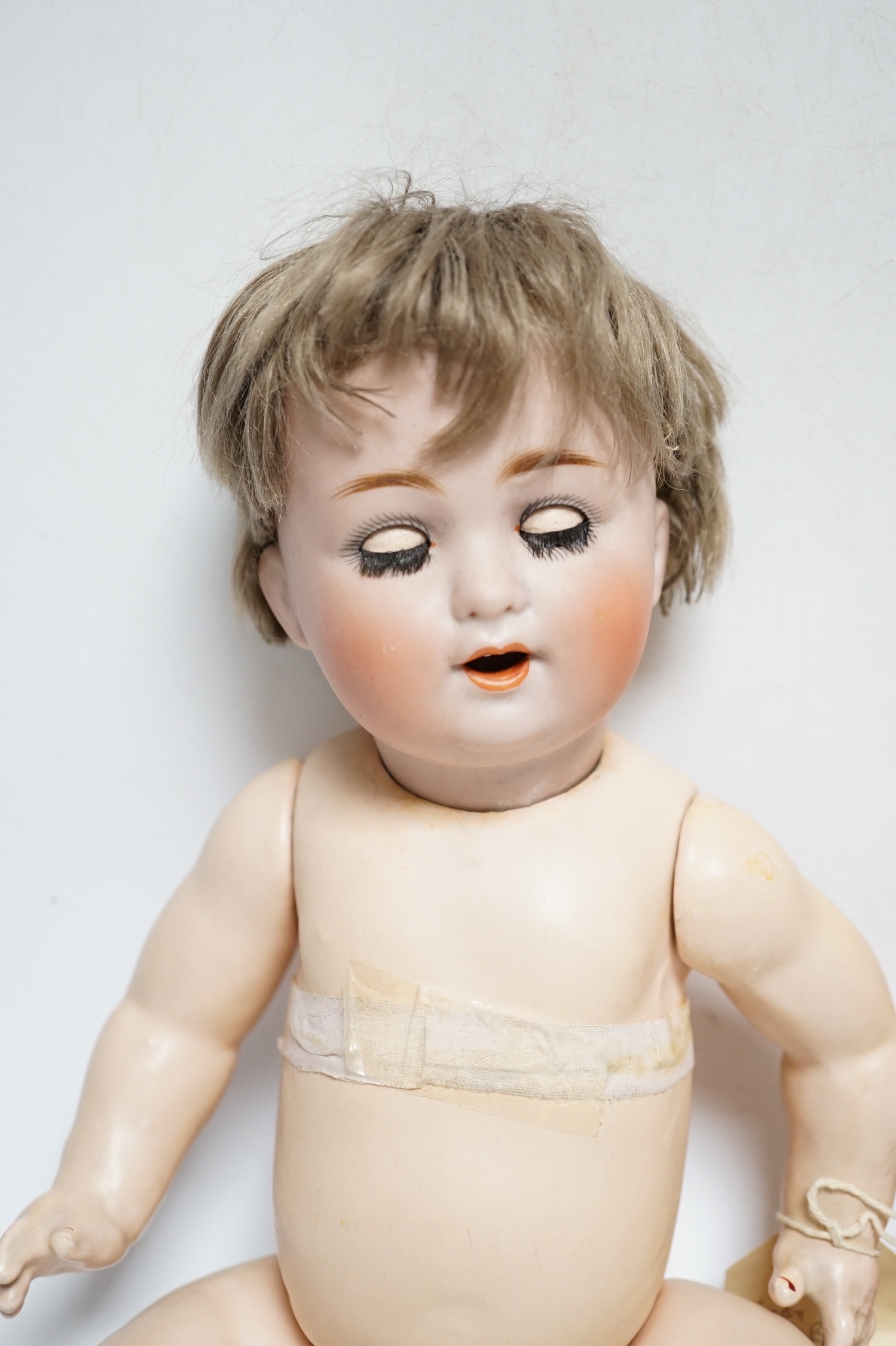 A Schutzmeister & Quendt bisque character doll, German, circa 1920 impressed 201, entwined SQ 6, with open mouth and two upper teeth, weighted blue glass eyes, fair mohair wig, curved limb composition body with voice-box